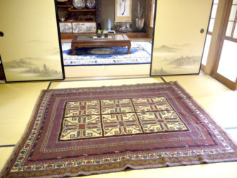 座敷に合うように敷いた深い紺とえんじ色のキリム。奥に敷いた青色の緞通とのバランスも良いです。